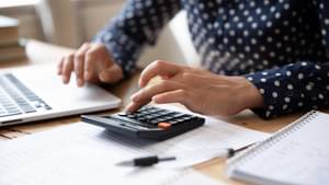 Ein Hand tippt auf einem Taschenrechner. 