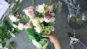 Eine Frau bindet einen frischen Blumenstrauß mit Rosen