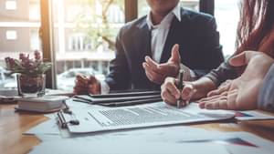 Einige Kolleginnen und Kollegen in Businesskleidung diskutieren an einem Konferenztisch.