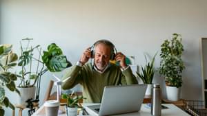 Ein Mann sitzt mit Kopfhörern vor einem Laptop in einem Büro mit vielen Pflanzen