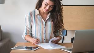 Junge Frau schaut sich Papiere zu ihrer Autofinanzierung an, um diese zu unterschreiben.