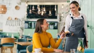 Die Besucherin eines Cafés bezahlt ihren Kaffee mit Karte.