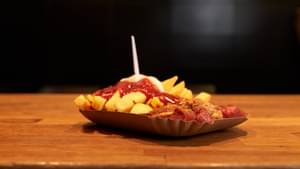 Currywurst mit Pommes rot-weiß in einer Pappschale