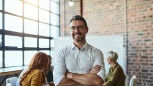 Unternehmer lehnt lässig an einem Konferenztisch und lächelt in die Kamera.