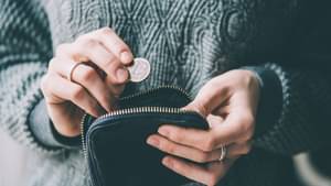 Hände, die eine Euro-Münze und einen kleinen Geldbeutel halten