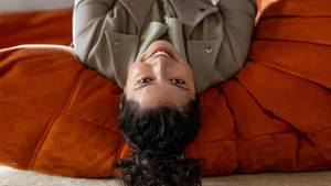 Eine Frau liegt rücklings auf einem Futon und schaut auf ihr Smartphone