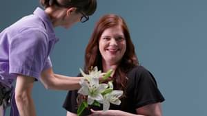 Jessica Beitzel wird für ein Foto hergerichtet und hält eineund hält weiße Lilien in der Hand.