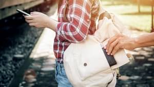 Nahaufnahme einer Frau mit Rucksack. Von hinten nimmt eine Hand einen Wertgegenstand aus dem Rucksack.