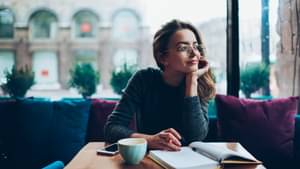 Junge Frau sitzt im Café und informiert sich über Anleihen