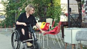 Laura Gelhaar sitzt in ihrem Handbike und greift nach einem Stuhl