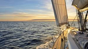 Ausblick vom Deck eines Segelbootes auf offener See, das dem Sonnenaufgang entgegensegelt. - Bootsfuehrerschein Kosten