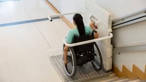 Eine Frau im Rollstuhl steht auf einem Plattformlift