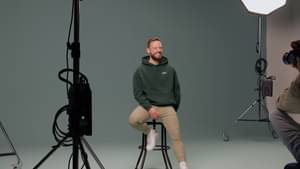 Dr. Dominik Kieu sitzt auf einem Hocker in einem Studio.