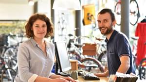 Eine junge Frau lässt sich in einem Fahrradgeschäft von einem jungen Verkäufer beraten.