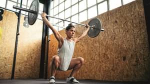 Eine junge Frau stemmt Gewichte mit einer Langhantelstange