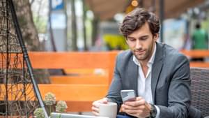 Junger Mann informiert sich mit seinem Smartphone über Wertpapiere