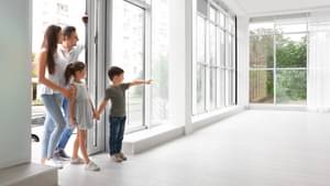 Junge Familie bei einer Wohnungsbesichtigung steht in der Tür zu ihrem potentiellen neuen Zuhause