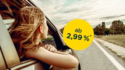 Junge Frau mit blonden Haaren sitzt auf der Beifahrerseite eines Autos und lehnt sich mit Arm und Kopf zum offenen Fenster raus: Autokredit ab 2,99% p.a.*