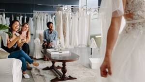 Eine Braut und ihre Freundinnen bei der Brautkleidanprobe in einem Geschäft.