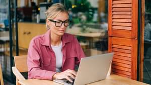 Eine Frau sitzt vor ihrem Laptop und tippt etwas