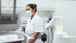 Zahnarzt, Zahnärztin -Helferin auf einem Stuhl im Behandlungszimmer