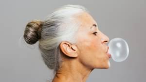 Ältere Frau im Seitenprofil machten mit einem Kaugummi eine Blase.