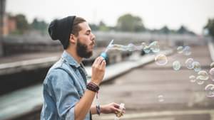 Junger Mann, der in der Stadt Seifenblasen bläst