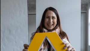 Christina Diem-Puello hält das Commerzbank-Logo vor sichund lacht herzlich in die Kamera.