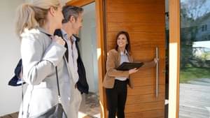 Paar besichtigt gemeinsam mit einer Maklerin ein modernes Haus